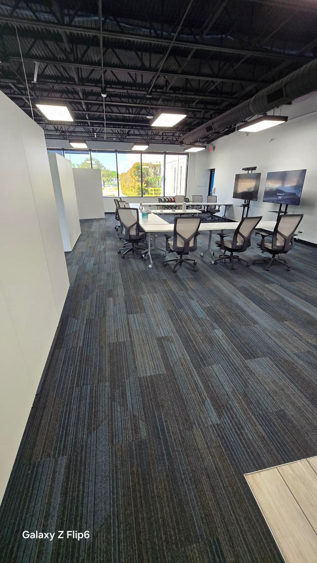 A hallway in an office building with sliding glass doors and a chair.
