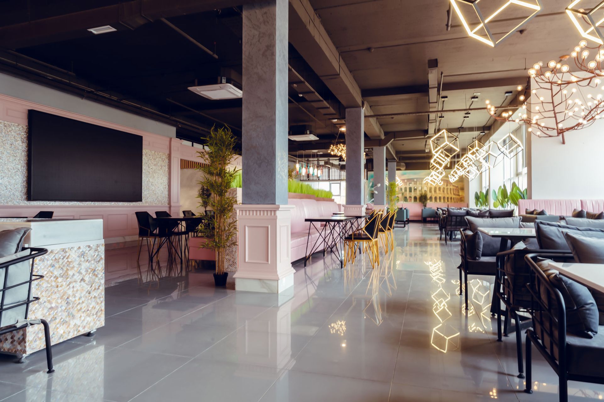 A large empty restaurant with tables and chairs and a flat screen tv on the wall.