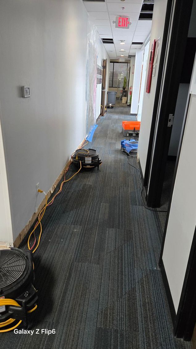 A hallway in an office building with sliding glass doors and a chair.