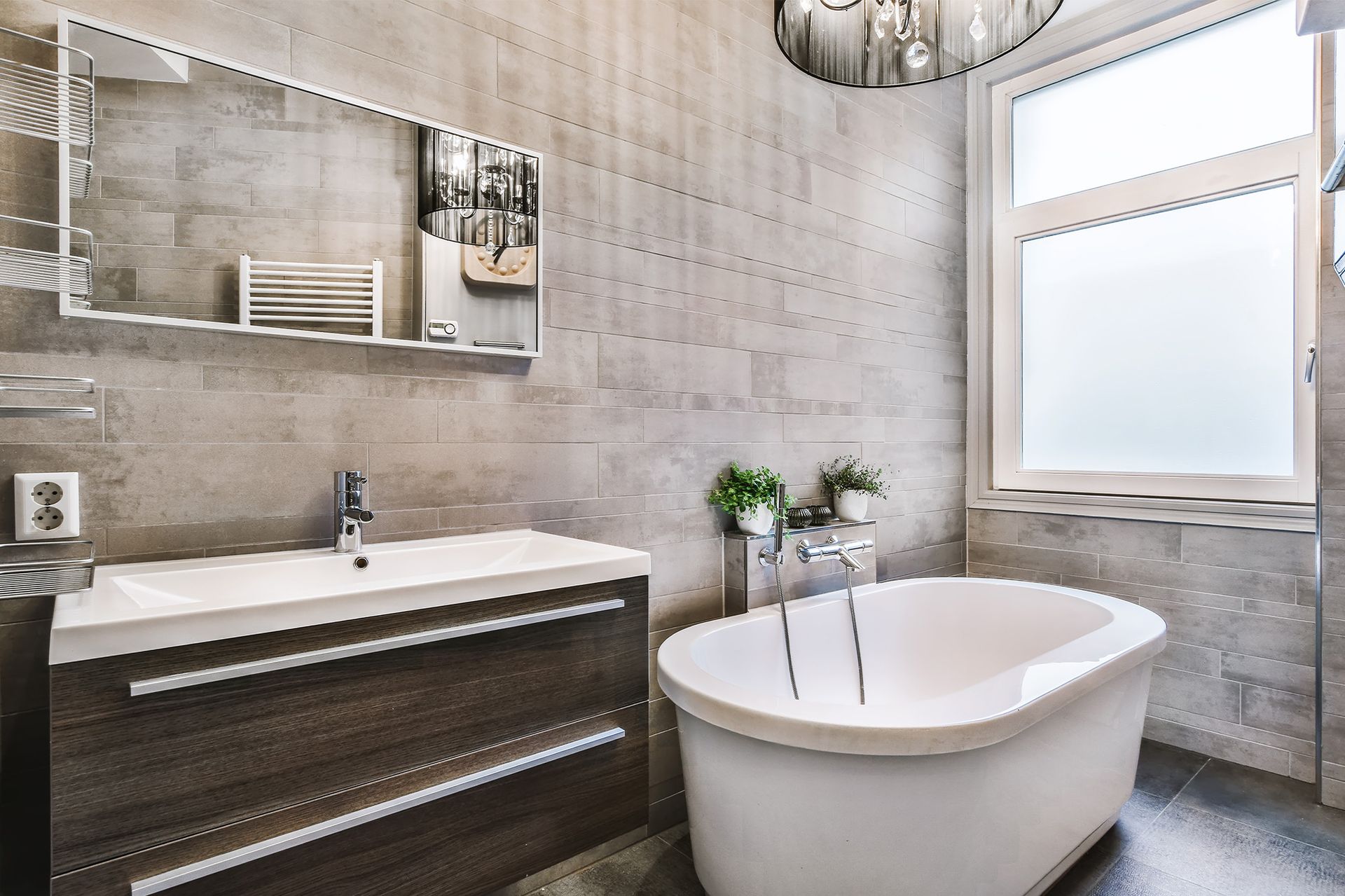 A bathroom with a tub , sink , mirror and window.