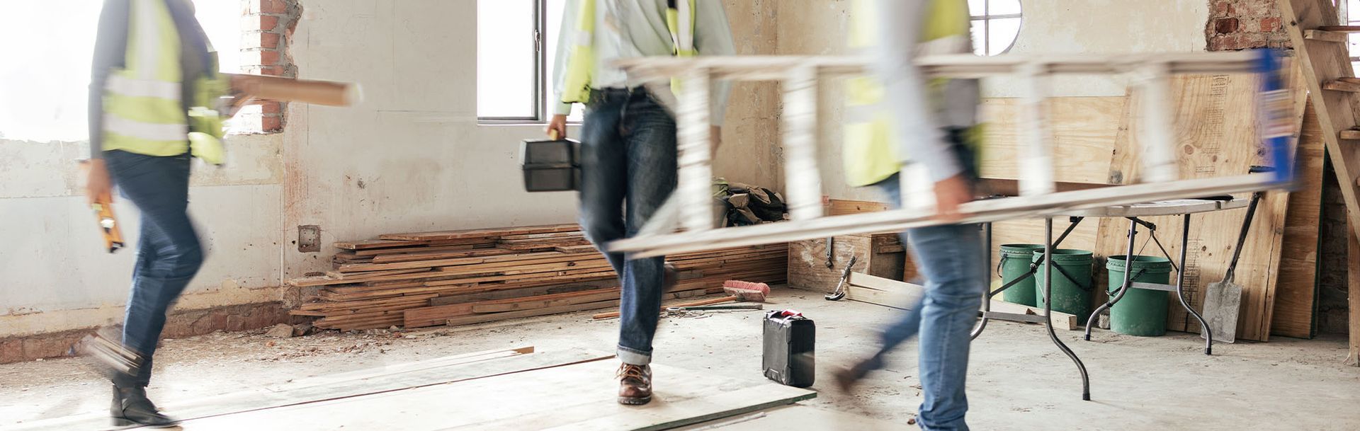 A group of people are carrying a ladder in a room.