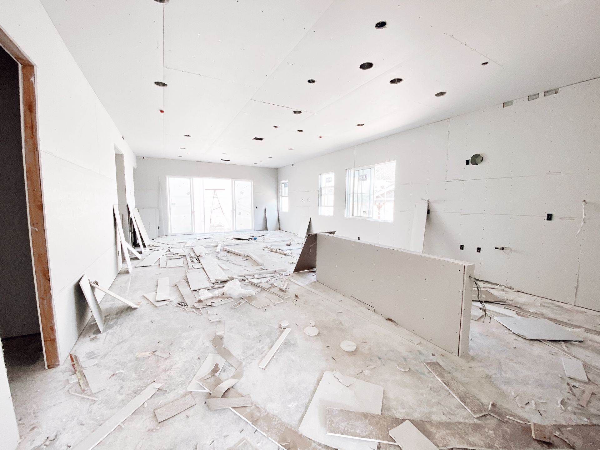 A large room with a lot of pieces of drywall on the floor.