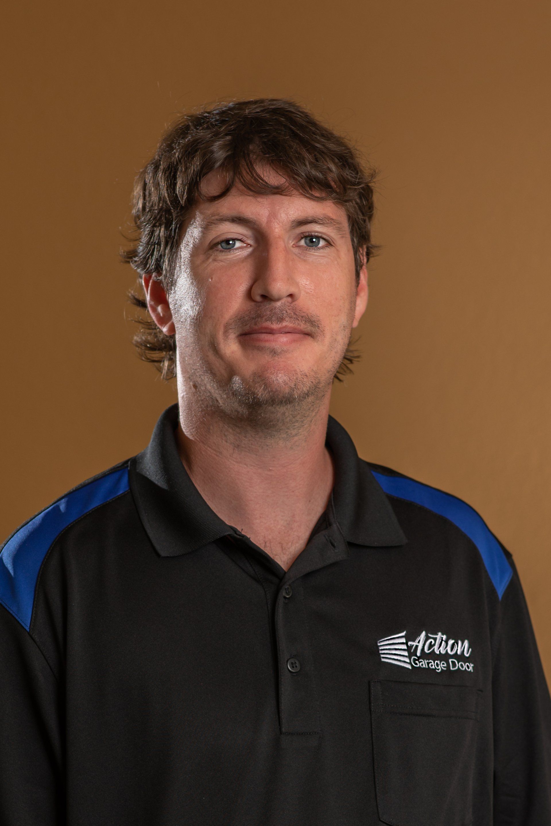 Man smiling next to Action Garage Door Services Sign in Central Arkansas