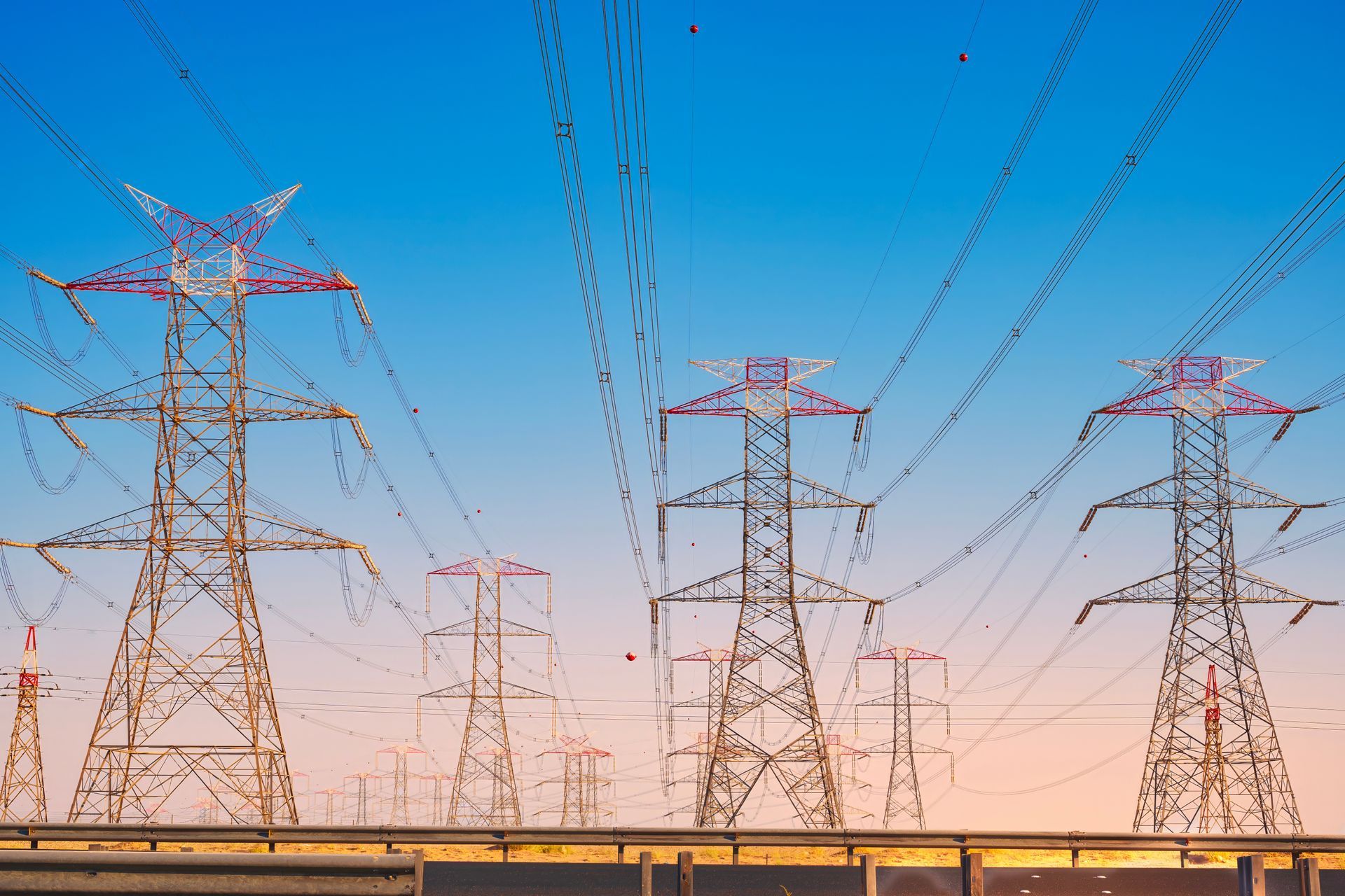 A row of power lines against a blue sky at sunset.