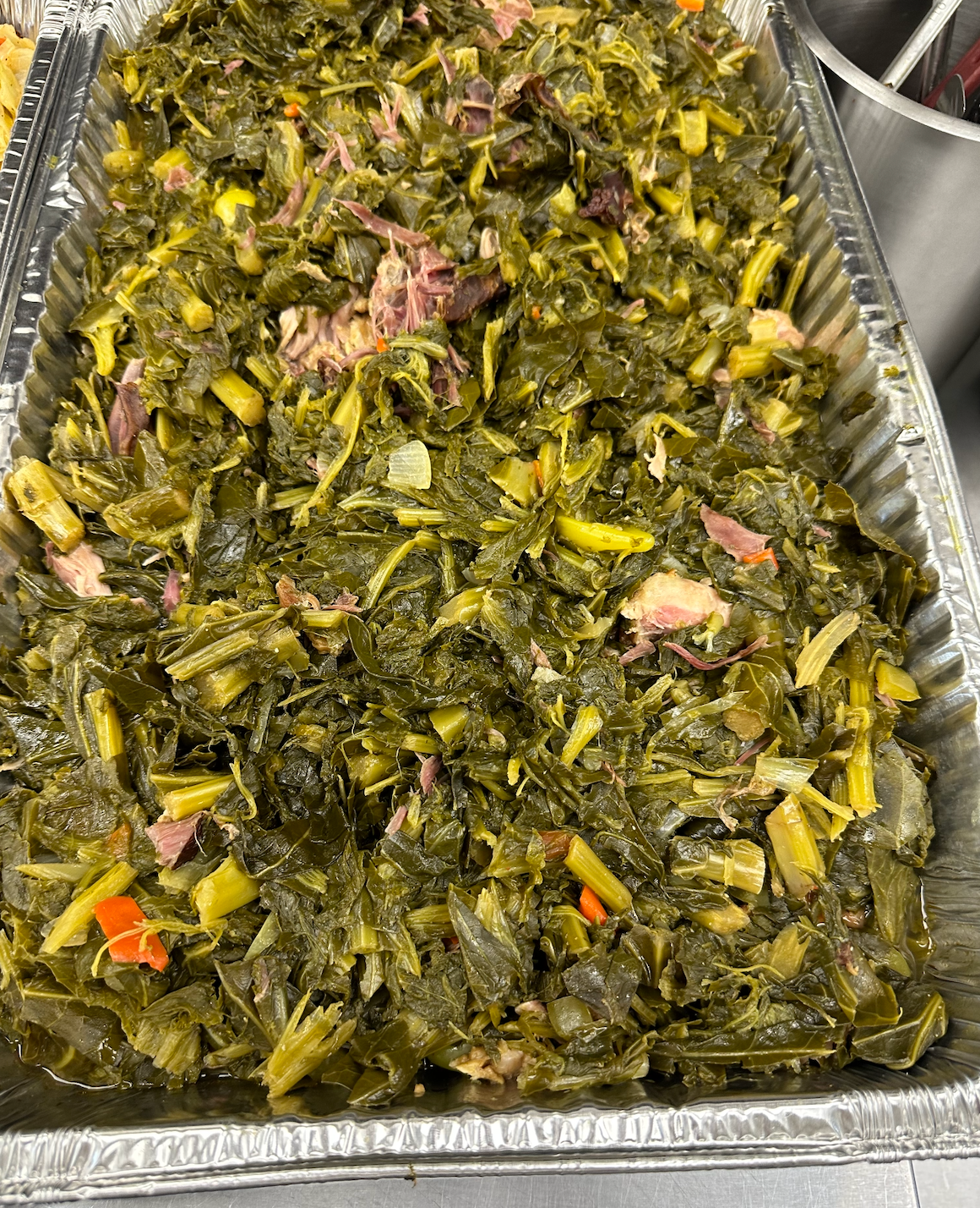 A pan filled with greens and meat on a table.