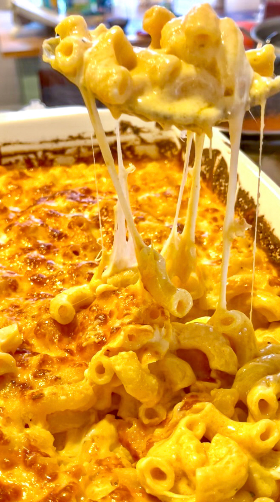 Macaroni and cheese is being scooped out of a casserole dish with a spoon.