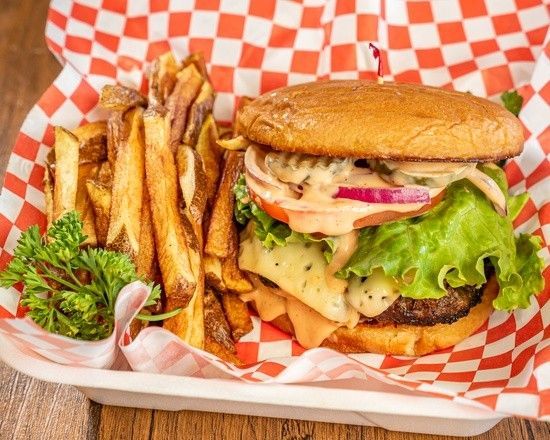 A hamburger and french fries on a checkered paper on a table.