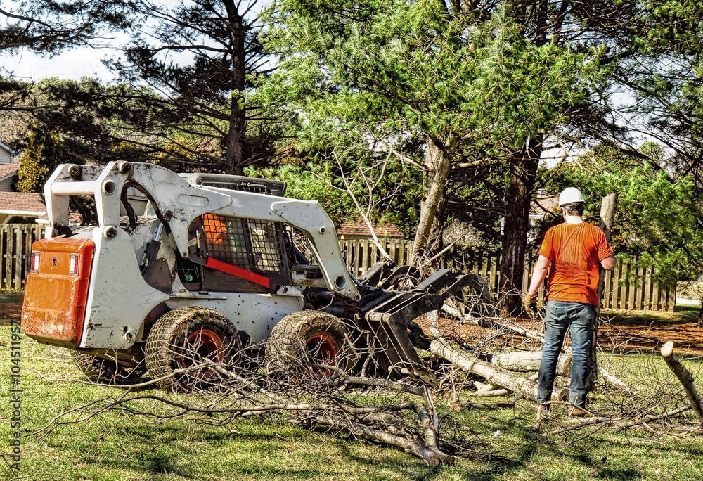A man is standing in front of a skid steer loader.