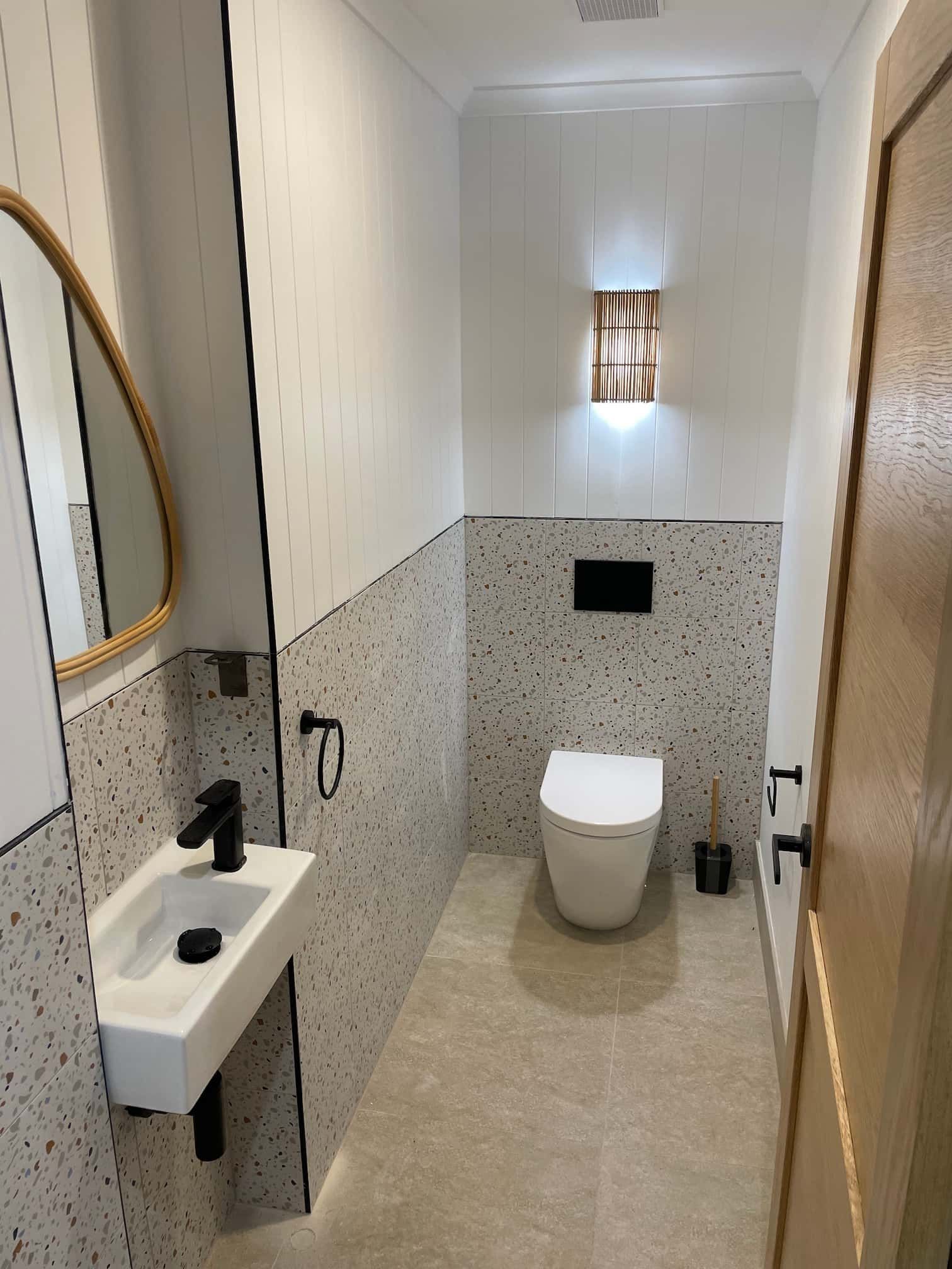 Small modern bathroom with a white toilet, black faucet, and terrazzo tile.