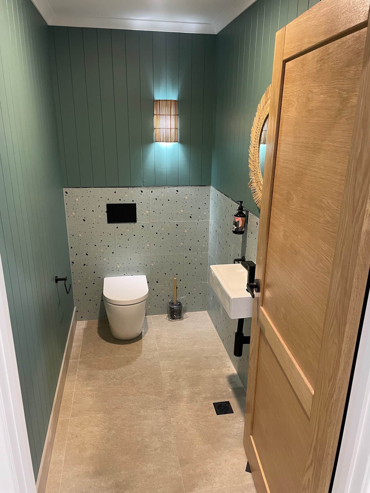 Small powder room with green patterned wallpaper and a wall-mounted toilet.