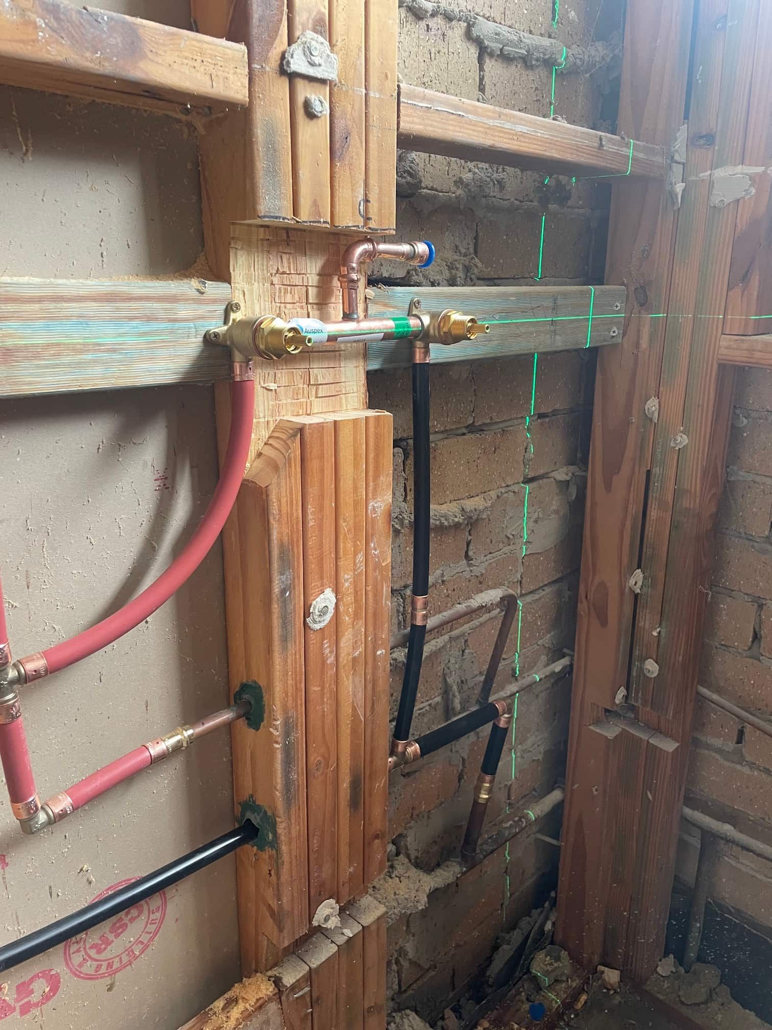 Modern bathroom with beige stone tile, wooden vanity, and glass shower.