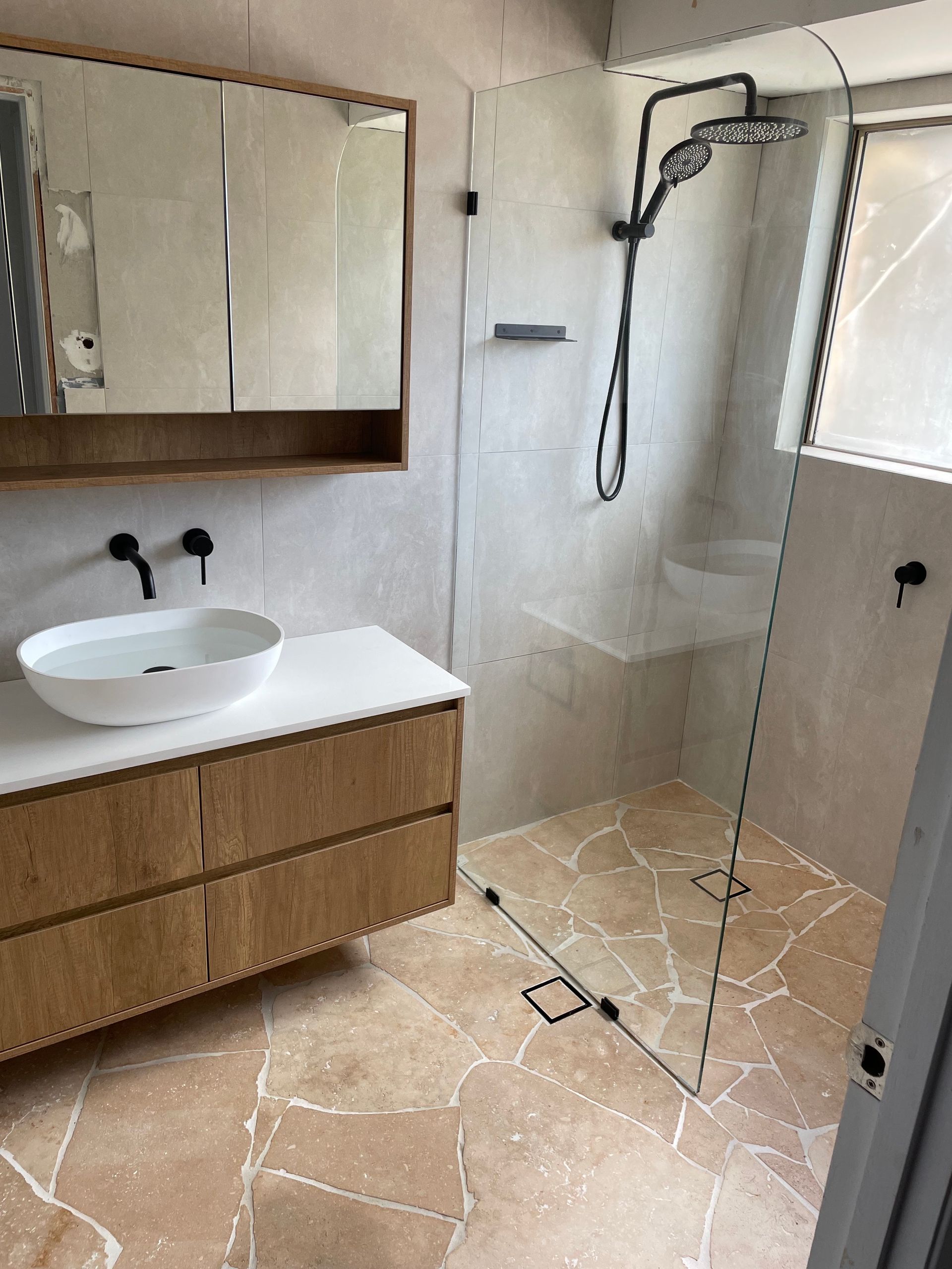 Arm under running water in a white sink, water splashing. Dark background with patterned sleeve.