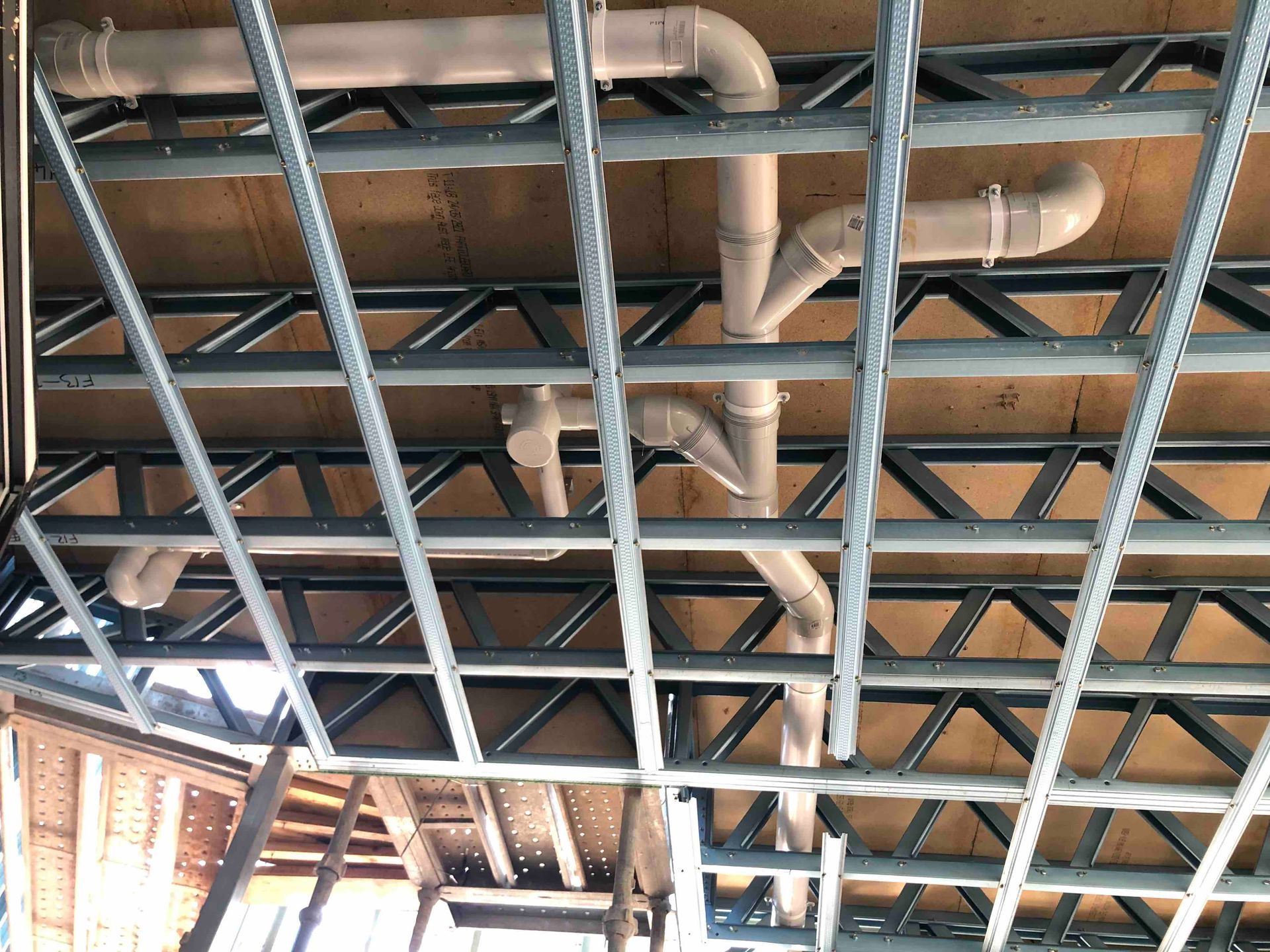 A rectangular excavated area with PVC pipes running through it, likely for plumbing, in a backyard setting.