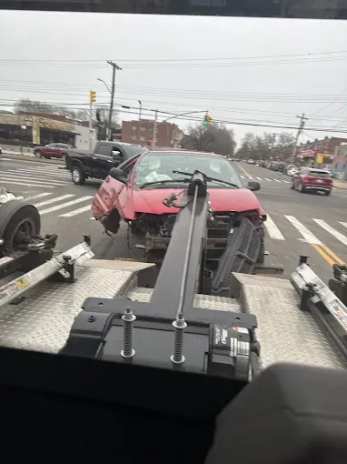 A red car is being towed by a tow truck.