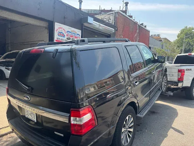A black ford expedition is parked in front of a building.