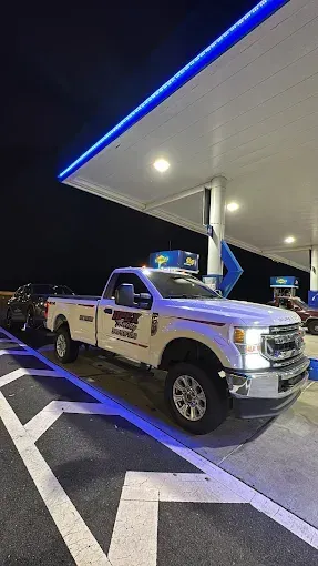 A white truck is parked in a parking lot at a gas station.