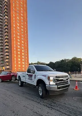 A white truck is parked in front of a tall building.