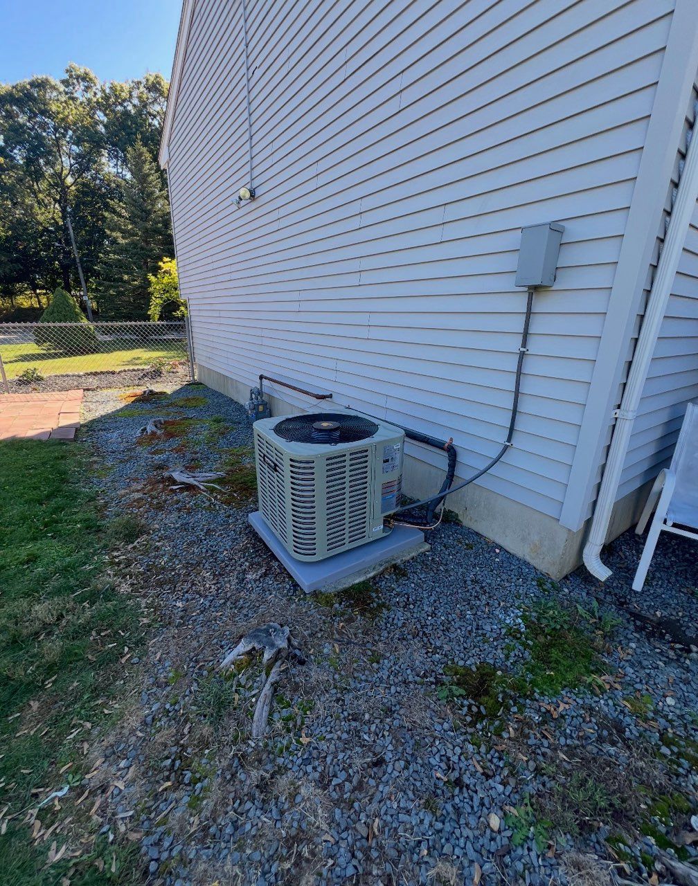 A living room with light brown walls, patterned furniture, a central coffee table, and dark curtains.