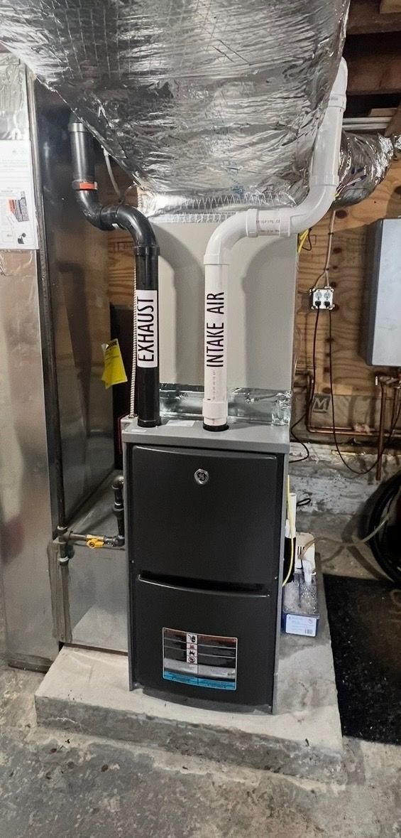 Mechanical room featuring a boiler, water heater, and wall-mounted plumbing controls against a concrete wall.