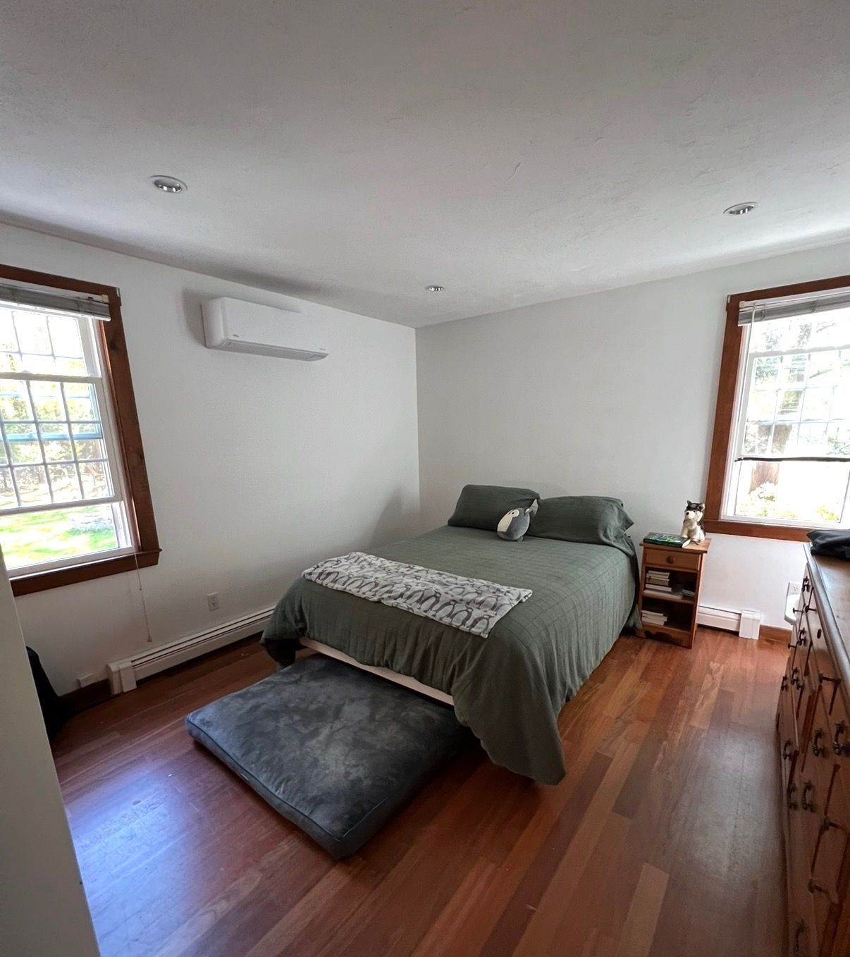 A hand holds up a detached, dirty mesh protective screen from an outdoor air conditioning unit with exposed coils.