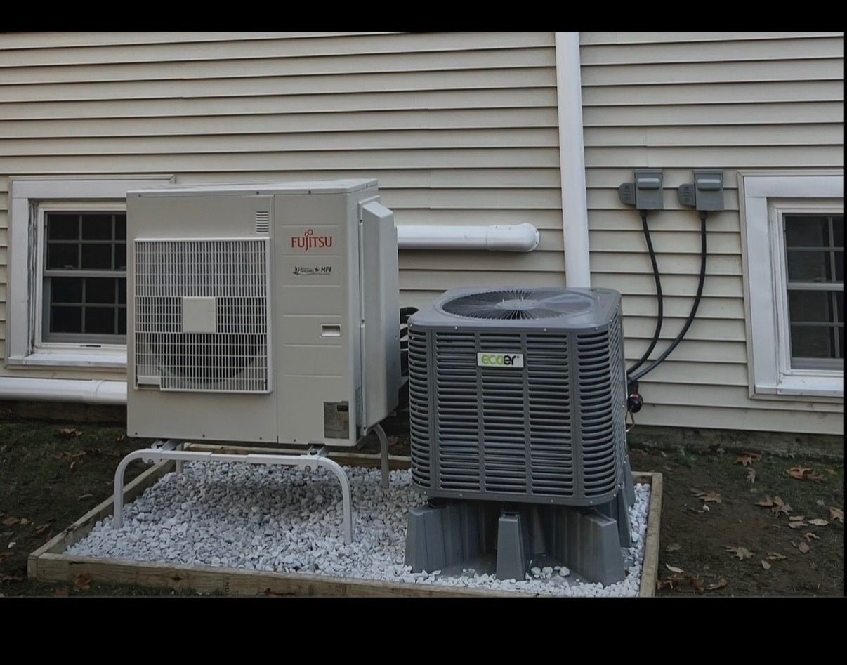 HVAC technician wearing a black uniform shirt works on a furnace in a basement utility area.