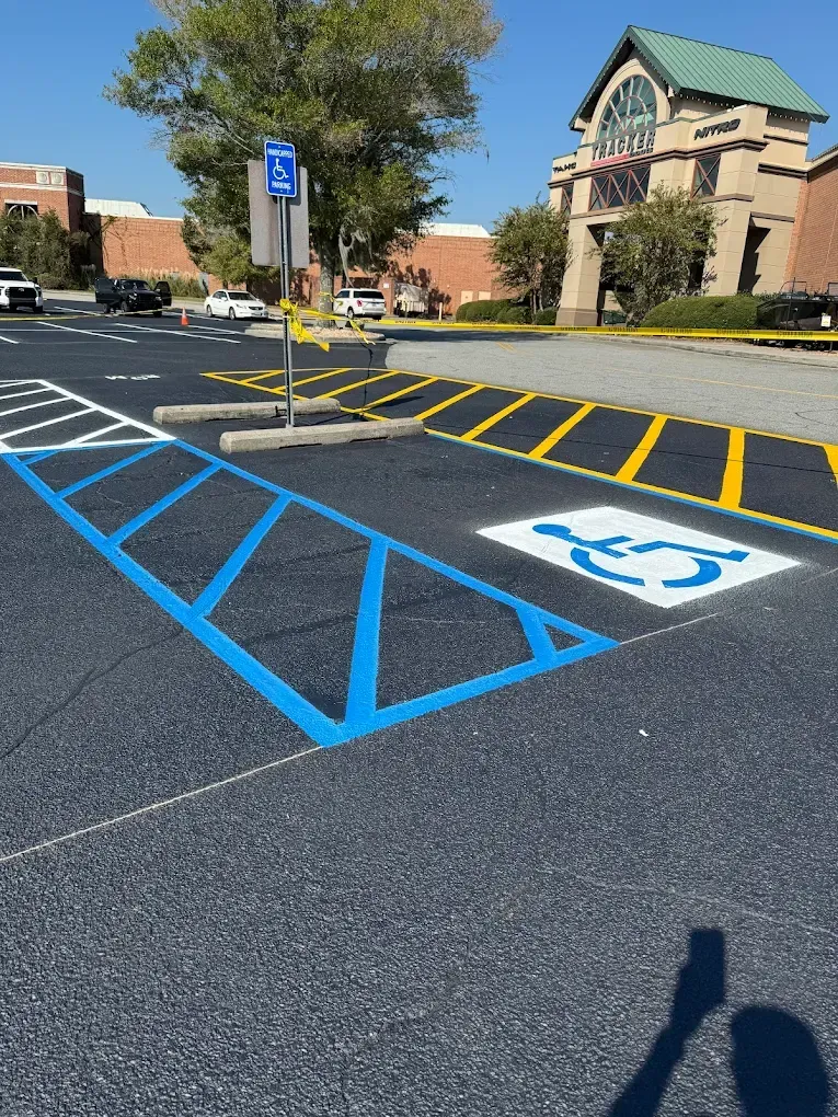 A parking lot with a blue-painted handicap space and access aisle, marked with a white wheelchair symbol and a blue sign.