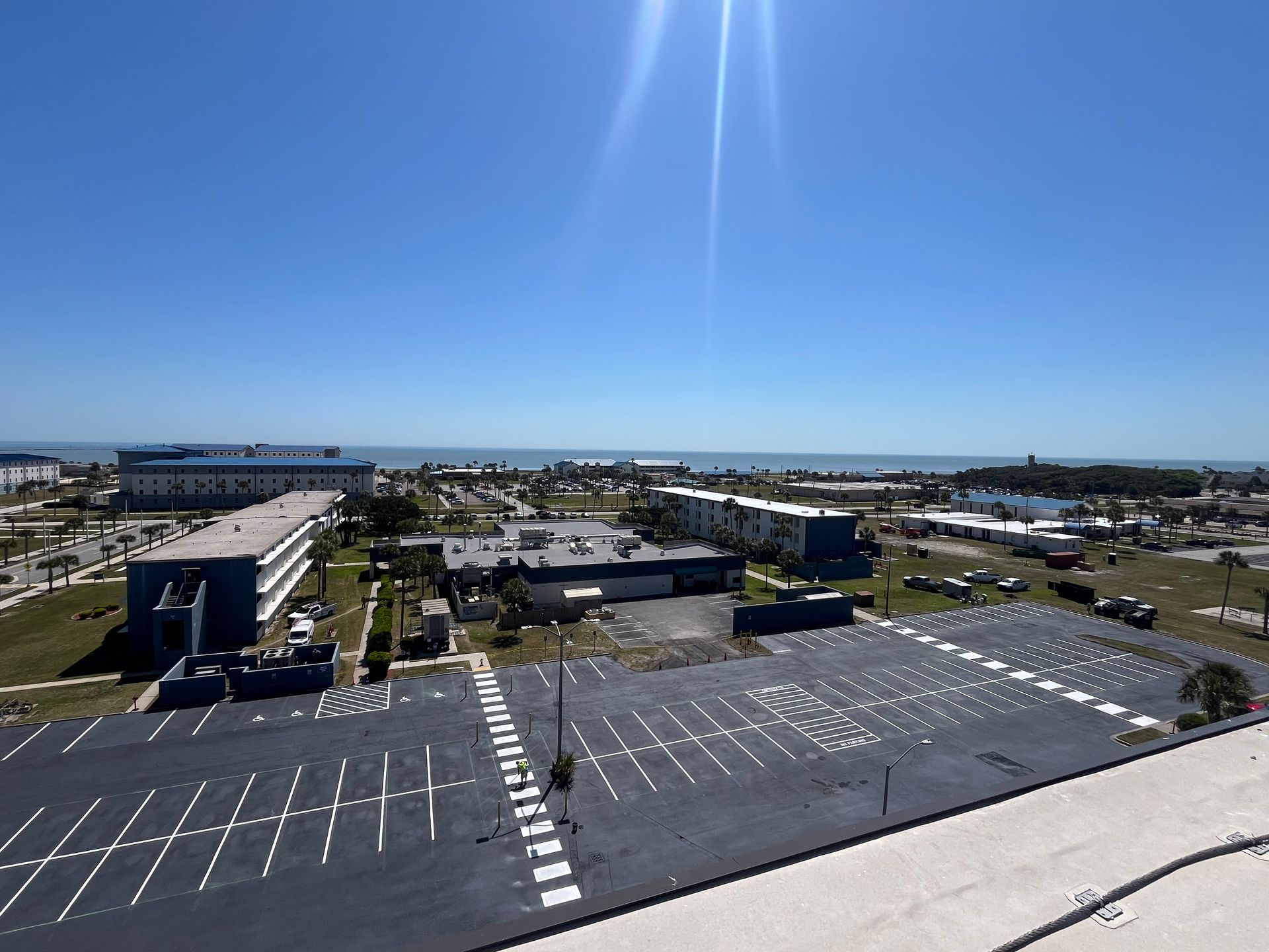 An empty parking lot with bright yellow painted lines marking rectangular parking spaces under a clear sky.