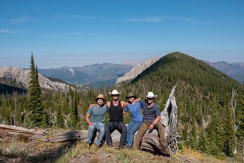 A group of people are posing for a picture on top of a mountain.