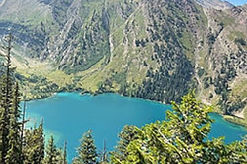 There is a lake in the middle of a mountain surrounded by trees.