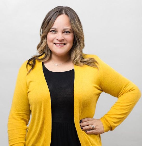 A woman wearing a yellow cardigan and a black dress