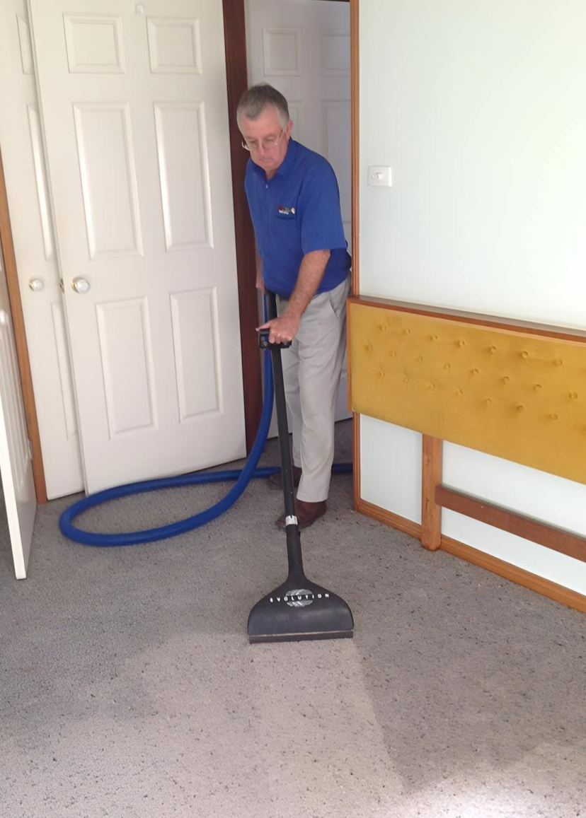A Man Wearing a Mask and Gloves is Plugging a Plug Into a Wall — Dryology Carpet Cleaning in Salamander Bay, NSW
