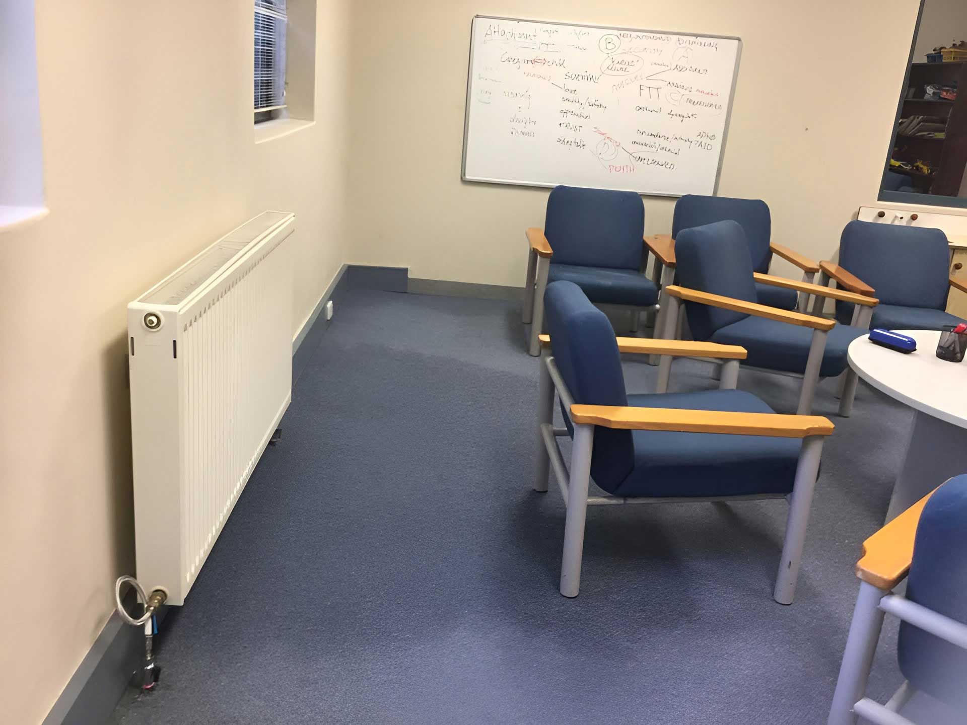 A Room With Blue Chairs And A White Board On The Wall With Wet Carpet — Dryology Carpet Cleaning in Maitland, NSW