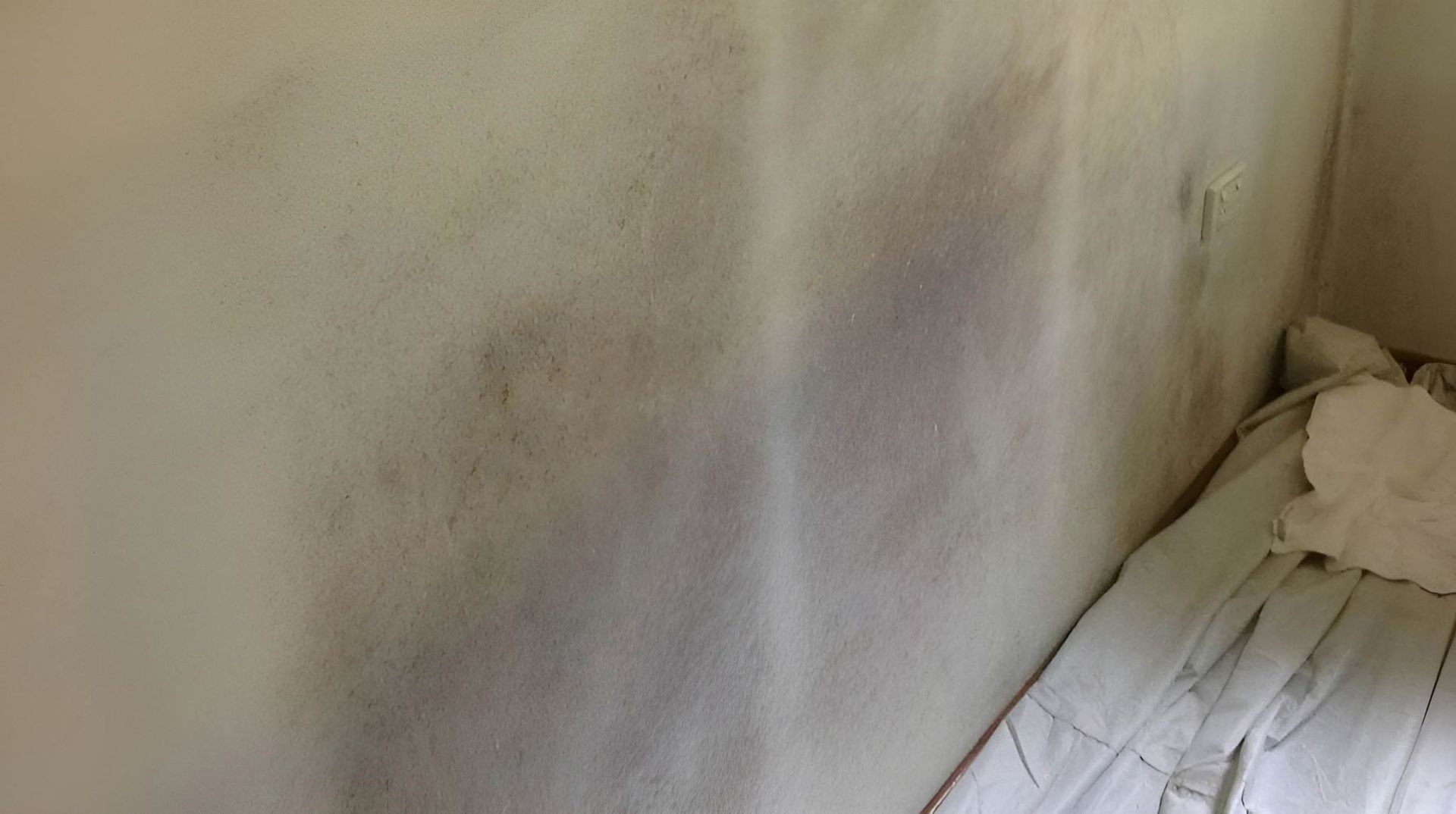 A Corner Of A Room With A Dirty Wall And A Bed — Dryology Carpet Cleaning in Cardiff, NSW