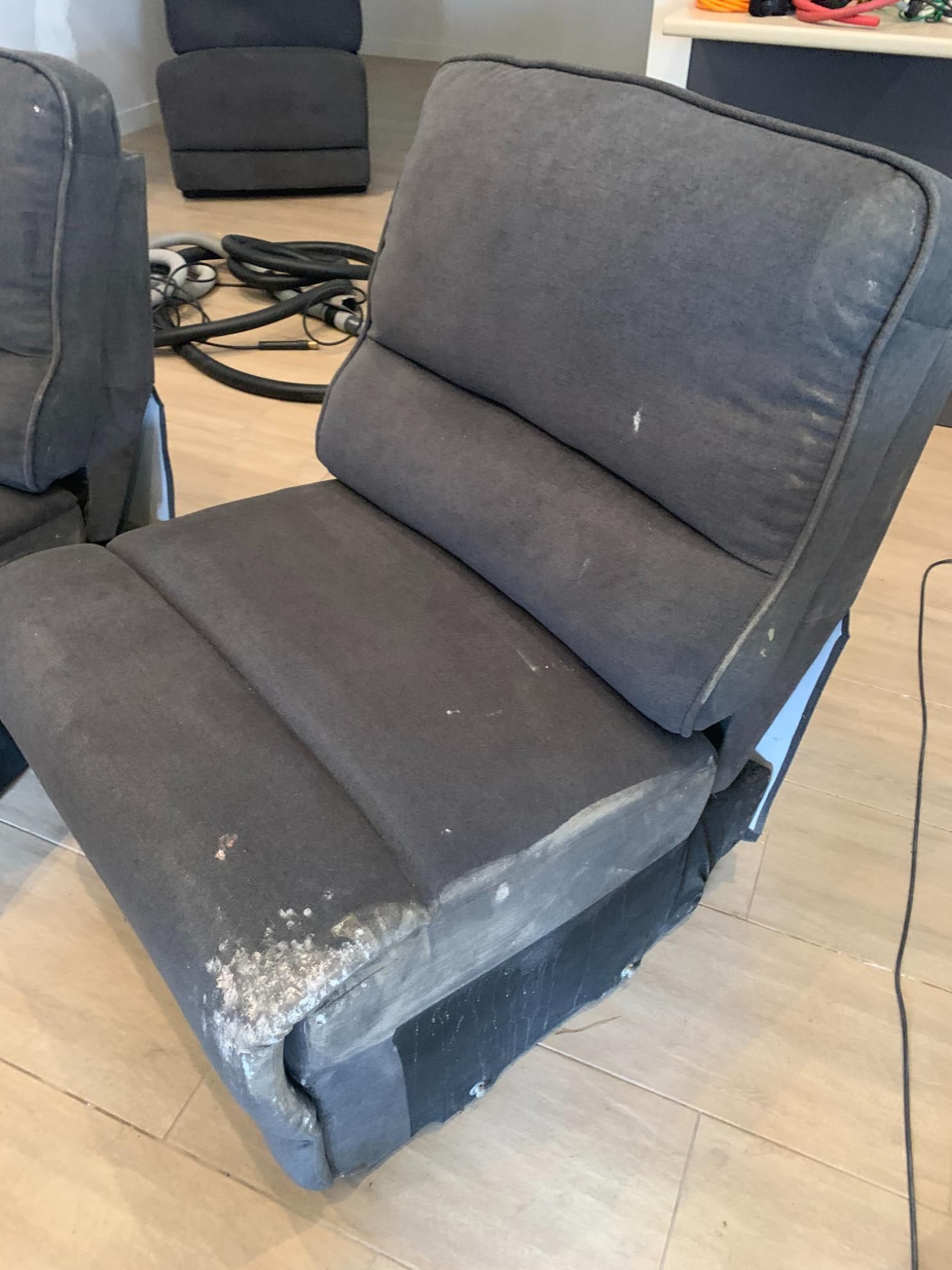 Gray upholstered chair, showing wear, in a room with a light wood floor — Dryology Carpet Cleaning in Salamander Bay, NSW
