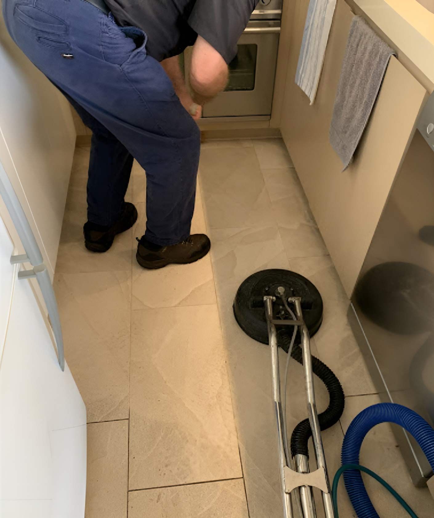 A Man Is Standing On A Tiled Floor Next To A Vacuum Cleaner — Dryology Carpet Cleaning in Kotara, NSW