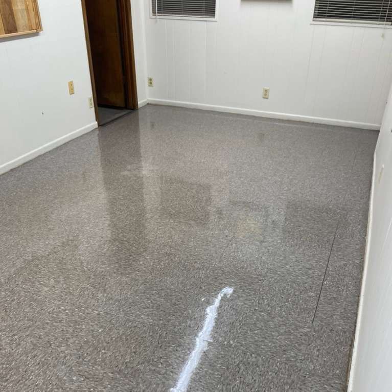 Room with polished, speckled gray concrete floor, white walls, door, and small windows.