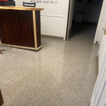 Office interior with shiny speckled floor, corrugated metal fronted desk, and doorway.