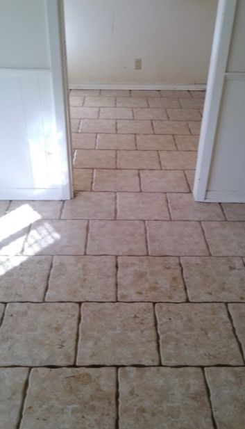 Beige tiled floor in a room, visible through a doorway, with white walls.