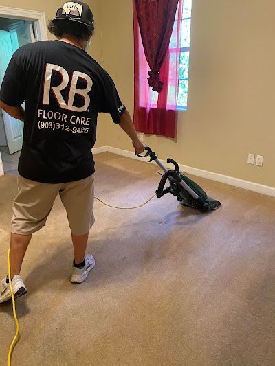 Man in black shirt vacuums a carpeted room with a machine.