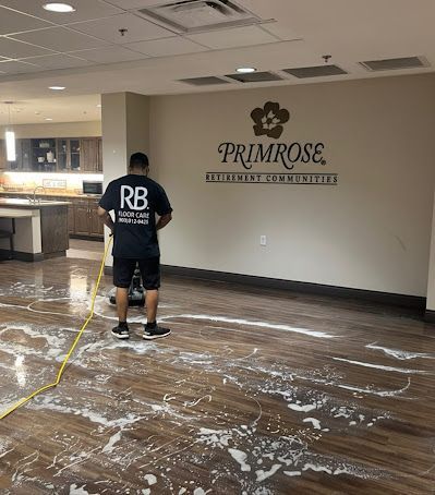 Man cleaning a wooden floor with soapy water in a Primrose Retirement Communities facility.