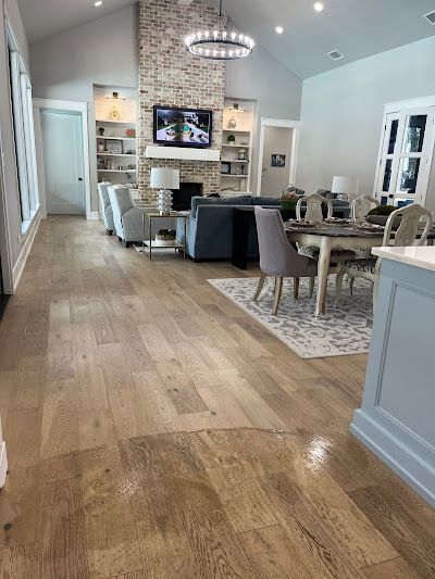 Hardwood floors in a spacious home with a brick fireplace, living room, and dining area.