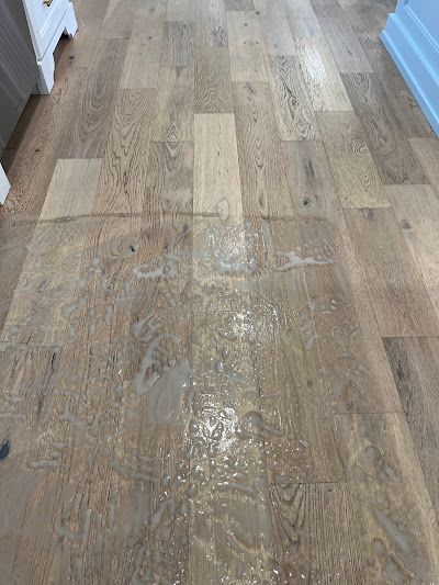 Wooden floor with water damage, light brown planks.