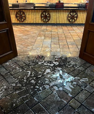 Open doorway revealing a restaurant with a wet floor. Soap suds and puddles on the tile.