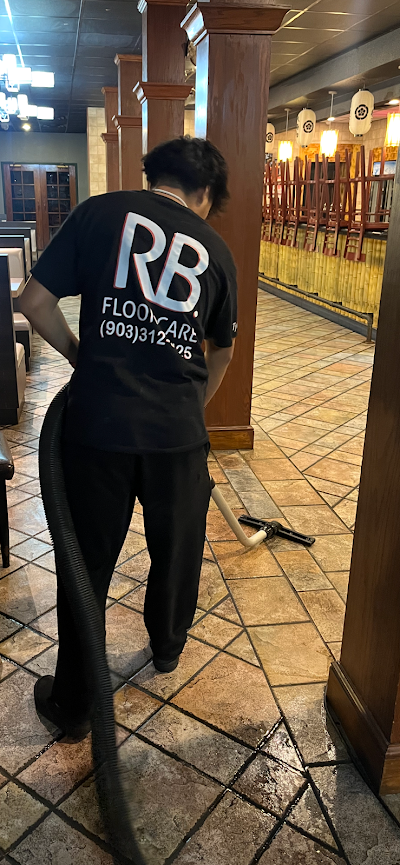 Person wearing a black RB shirt vacuums a tiled floor inside a restaurant.