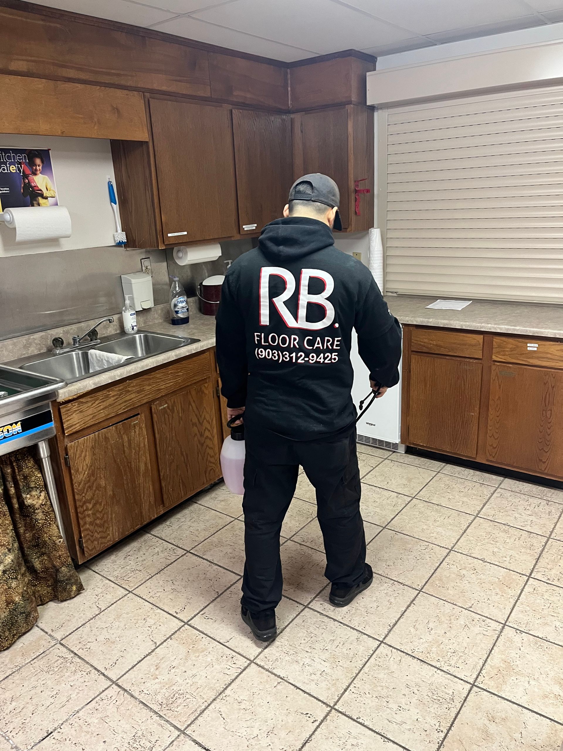A man in a black rb hoodie is standing in a kitchen.