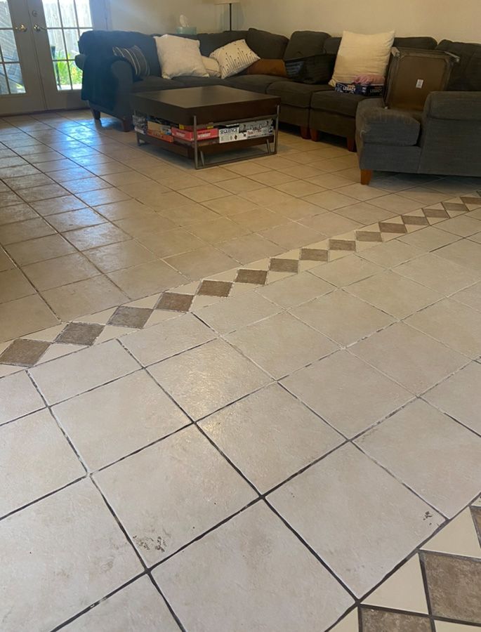 Tiled floor with a diamond border leading to a living room with a sectional sofa and coffee table.