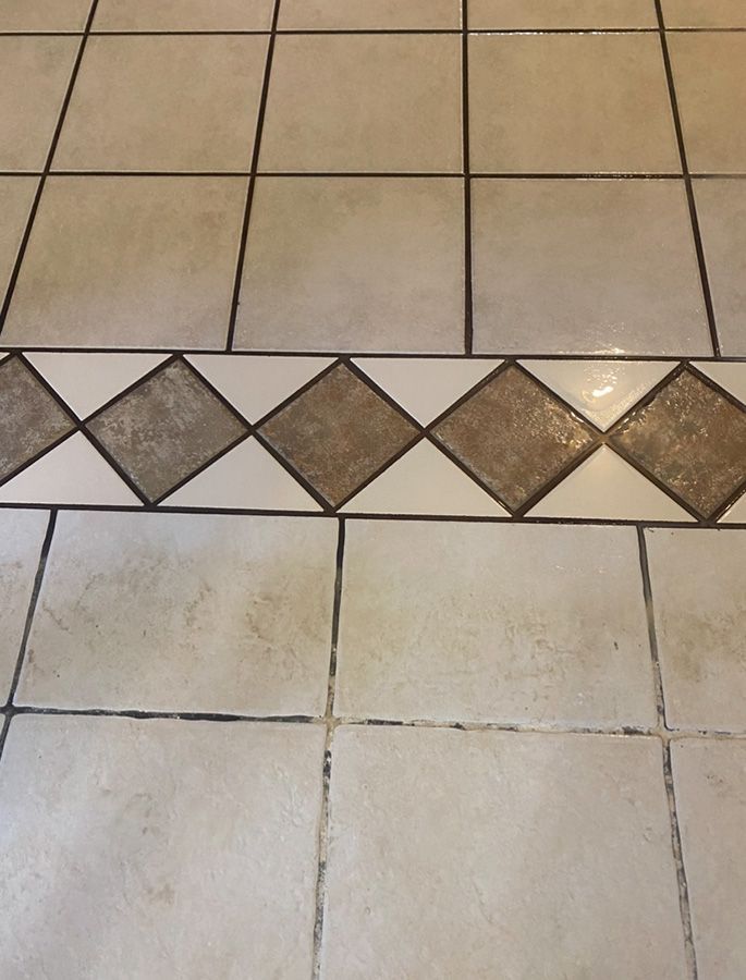 Tiled floor with a diamond-patterned border. Light beige tiles with dark grout.