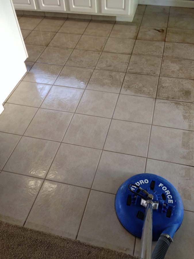 Tile floor being cleaned with a blue Hydro Force cleaning machine; one half is clean, the other dirty.