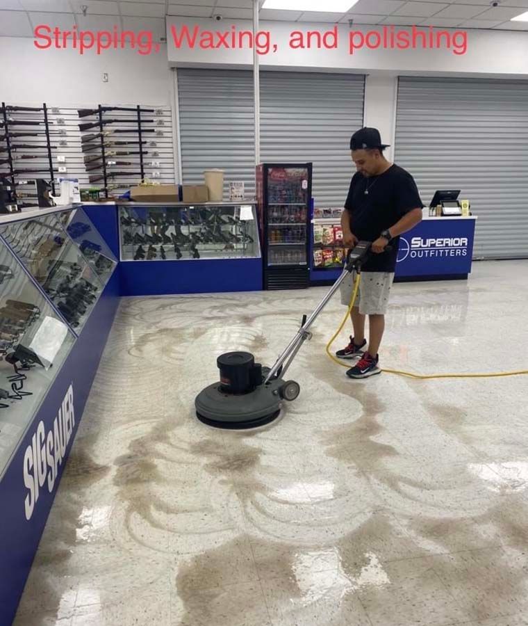 Man stripping, waxing, and polishing a store floor with a machine.