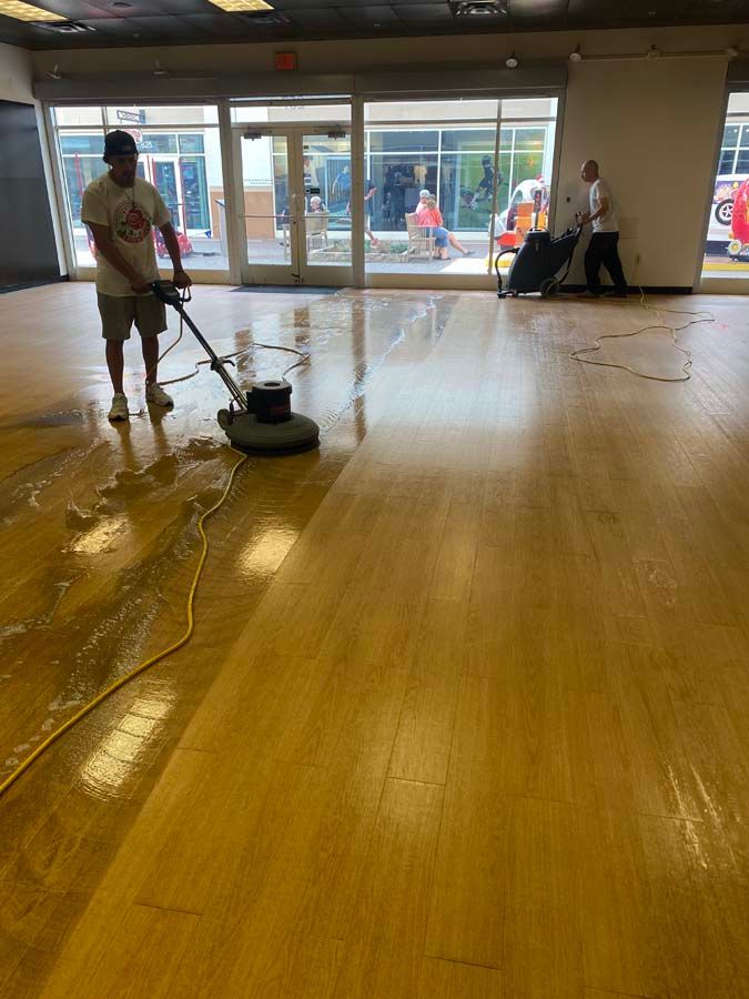 A man is cleaning a wooden floor with a machine.